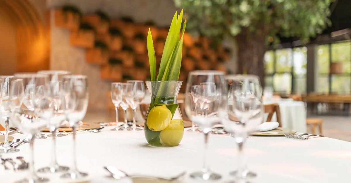 Une table magnifiquement décorée dans un restaurant, avec des citrons et un vase en verre en centre de table.
